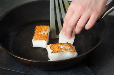 Pan fried golden fish fillet cubes, frying in real butter, in a non stick rustic pan.