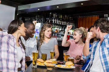 Happy friends having a drink and watching sport