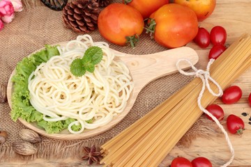 Spaghetti and raw spaghetti on wood background