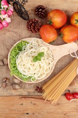 Spaghetti and raw spaghetti on wood background
