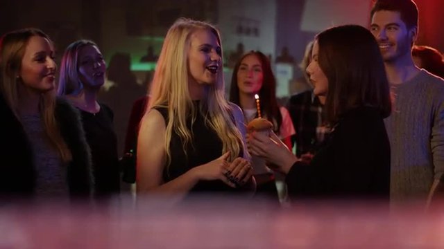 attractive blond girl in club receives congratulations from friends