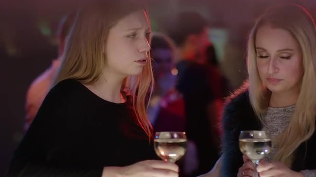 sad girl at bar in club is comforted by a friend