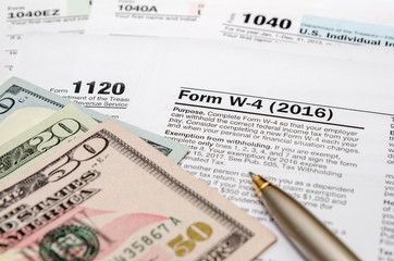 tax form w4, 1040, 1120 with pen and us dollar