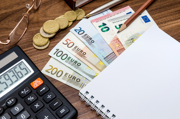 Office tools with empty notebook and euro bills on wooden table