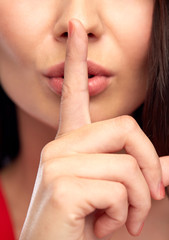 close up of woman face holding finger on her lips