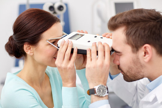 optician with pupilometer and patient at eye clinic