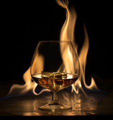 A glass of brandy and ice, on a background of fire