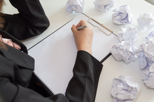 Hands of female writing with crumple paper at the desk