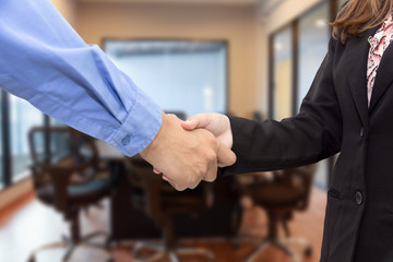 Close up of businessmen shaking hands in meeting room