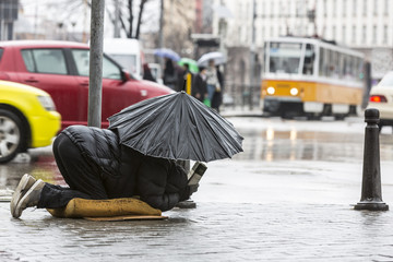 Beggar in the rain with umbrella traffic - obrazy, fototapety, plakaty