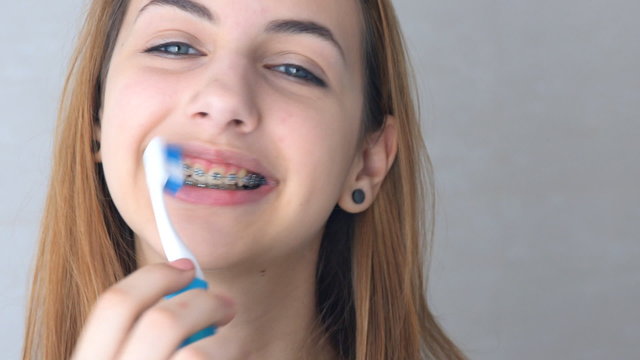 Beautiful smiling girl with retainer for teeth brushing teeth .
