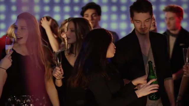 young people on dancefloor at club filling champagne glasses and celebrating