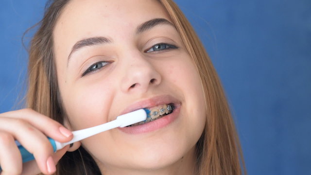 Beautiful smiling girl with retainer for teeth brushing teeth .