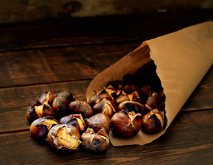 roasted chestnuts in paper bags on a wooden background
