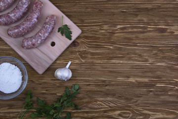 Raw sausages, salt and garlic on wooden table
