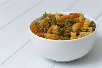 Raw fusilli pasta in a white bowl