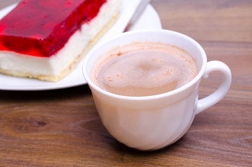 A cup of cappuccino coffee with slice of  cake