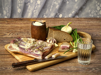 the salty bacon with onions and black bread on the wooden cuttin