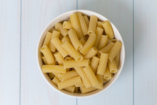 Raw tortiglioni pasta in a white bowl