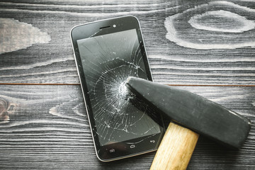 Smartphone with broken display on the wooden rustic background