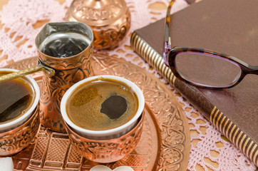 Obraz na płótnie Canvas Coffee served in copper pottery and a book
