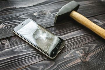 Smartphone with broken display on the wooden rustic background