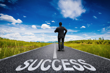 success concept with businessman standing on long road