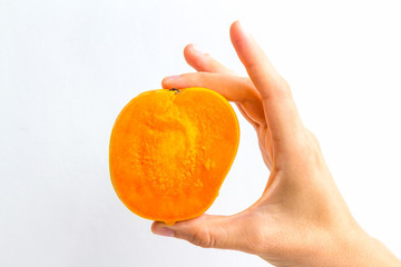 A very ripe mango, sliced in half, held in the hand of a young woman, isolated on white.