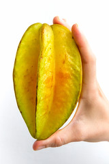 A carambola, commonly known as starfruit, held upright in the hand of a young woman, isolated on white.