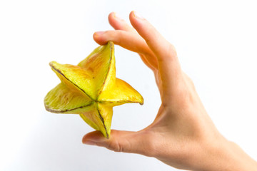 A carambola, commonly known as starfruit, held on its side, in the hand of a young woman, isolated on white.