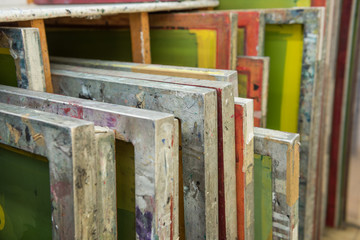 Silk screen printing screens stored in a wooden rack ready for printing. - obrazy, fototapety, plakaty