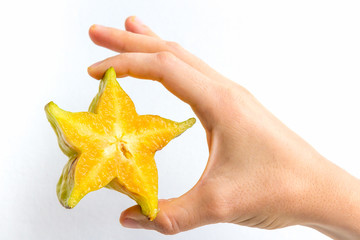 A starfruit cut in half, held in the hand of a young woman, isolated on white.