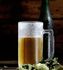 beer in glass, bottle and hops on a wooden background