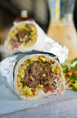 Mexican shredded beef breakfast burrito sliced in half served with ice coffee.