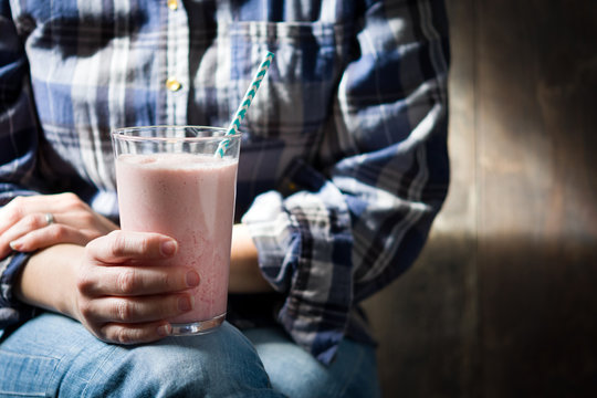 A person holding a strawberry milkshake