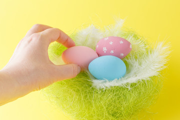 Fototapeta premium Hands holding modern painted easter egg in a small nest
