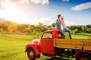 Senior couple sitting in back of red pickup truck