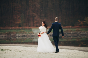 Love and passion - kiss of married young wedding couple near lake