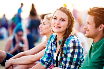 Teenagers at summer music festival, sitting on the ground