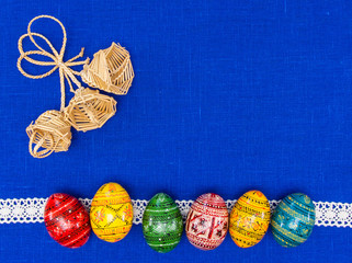 Blank, greeting easter card with straw bells, easter eggs in blue textile background