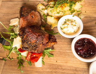 Salted piece of meat lying on a cutting board together with potatoes and sauce