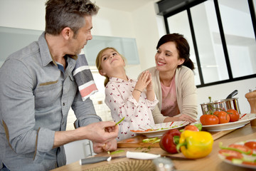 Parents with child cooking together at home
