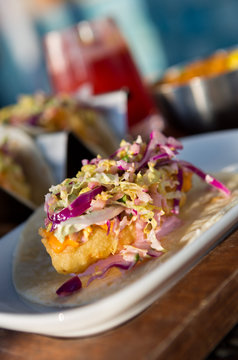 Mexican fried cod fish taco served with lettuce, red onion and sauce
