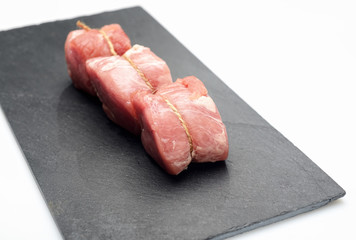 raw fillet medallions on the board of black basalt
