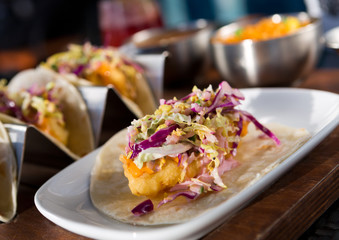 Mexican fried cod fish taco served with lettuce, red onion and sauce