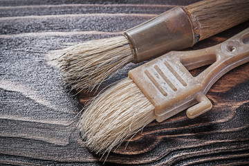 Age-old paint brushes on wooden board construction concept