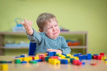 Tearful boy in nursery with toys
