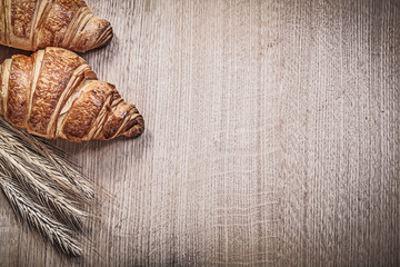 Composition of ripe wheat rye ears croissants on wooden board