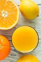 Fresh orange and lemon mix juice in a glass, white wooden background