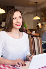 Young happy woman using notebook in cafe